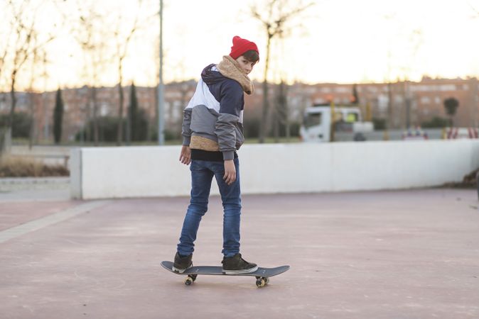 Back of young man riding on skateboard in park
