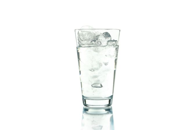 Tall glass full of ice water on blank background