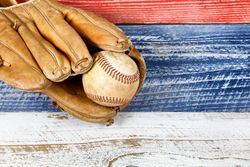 Weathered baseball mitt and ball on faded boards painted in American national colors