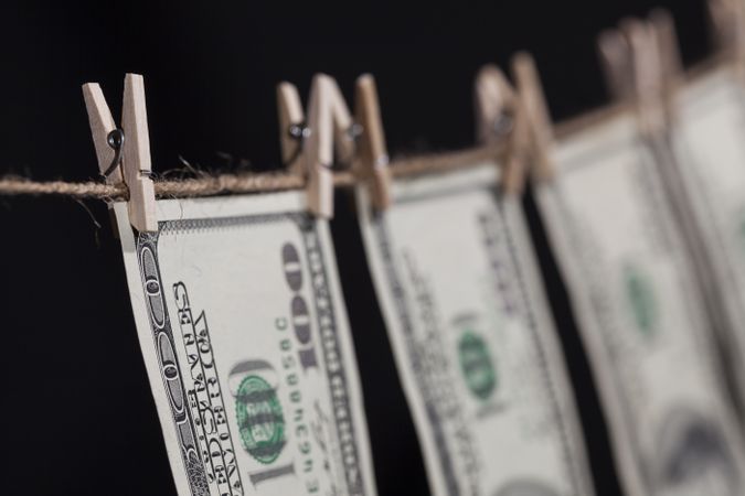 Hundred Dollar Bills Hanging From Clothesline on Dark Background