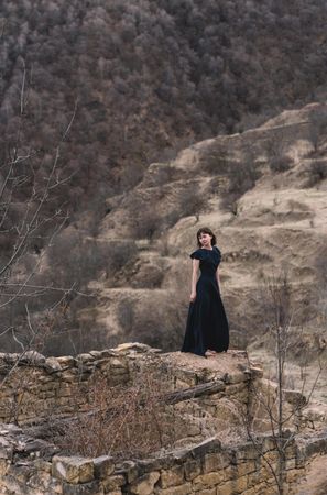 Woman in long blue dress standing near abandoned structure