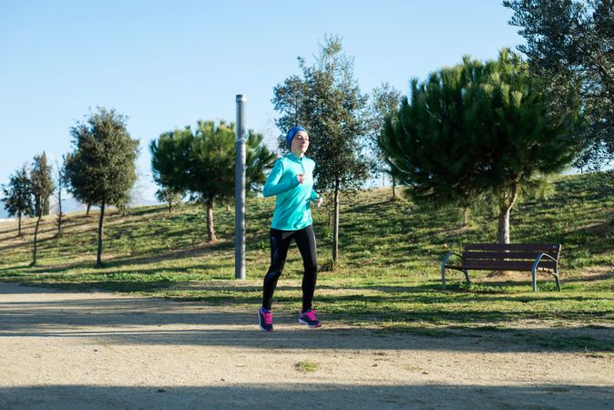 Woman in ear warmers running outdoors on sunny fall day