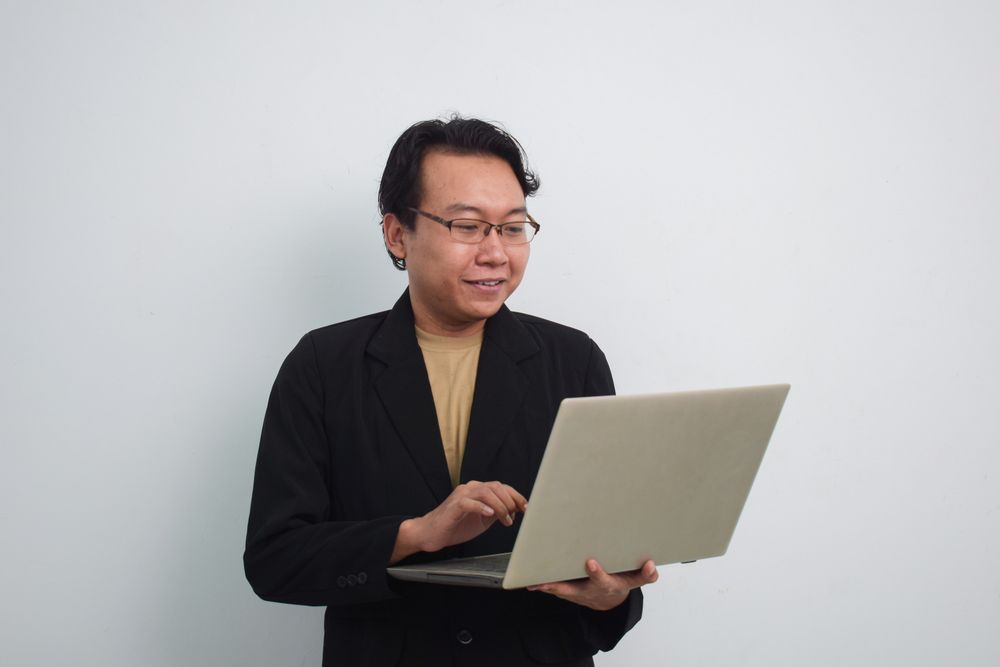 Happy Asian businessman reading on laptop