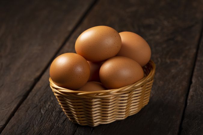 Basket with brown chicken eggs goes up the table.
