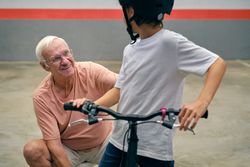 Cheerful grandfather with faceless boy on bicycle