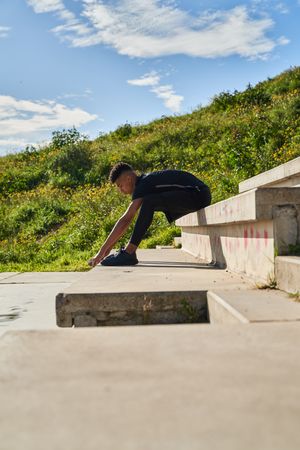 Sportive Hispanic man stretching on steps