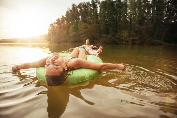 Portrait of smiling young girl floating in an innertube with a man at the background in a lake