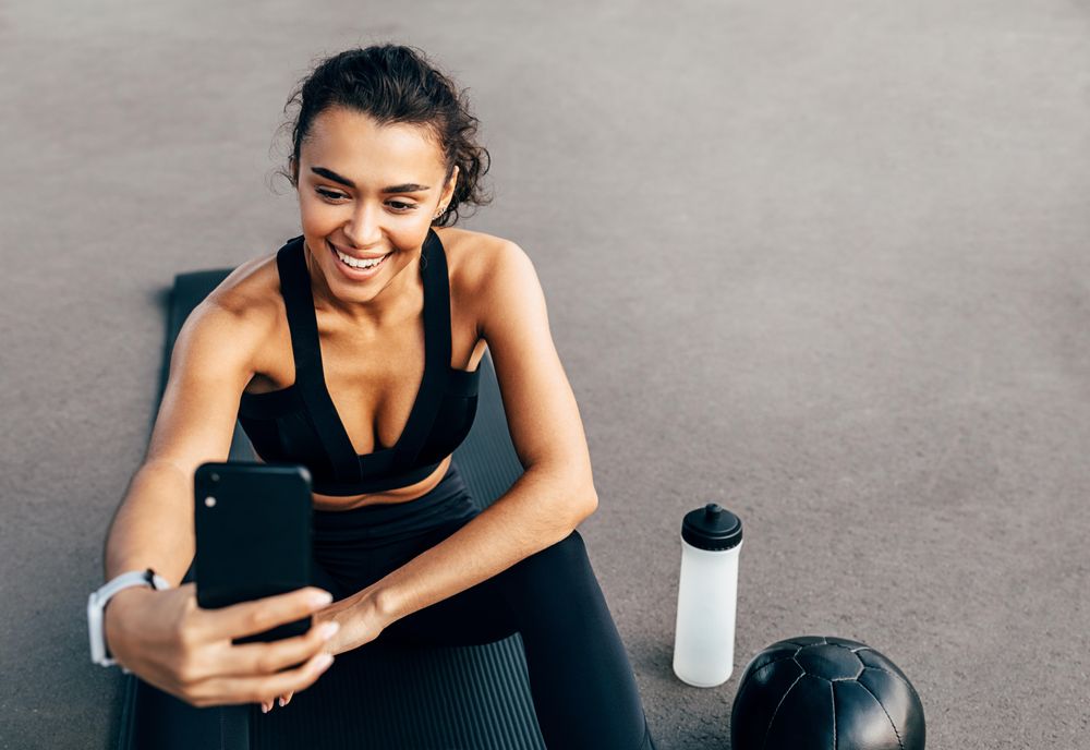 Woman in athletic gear taking selfie on yoga mat