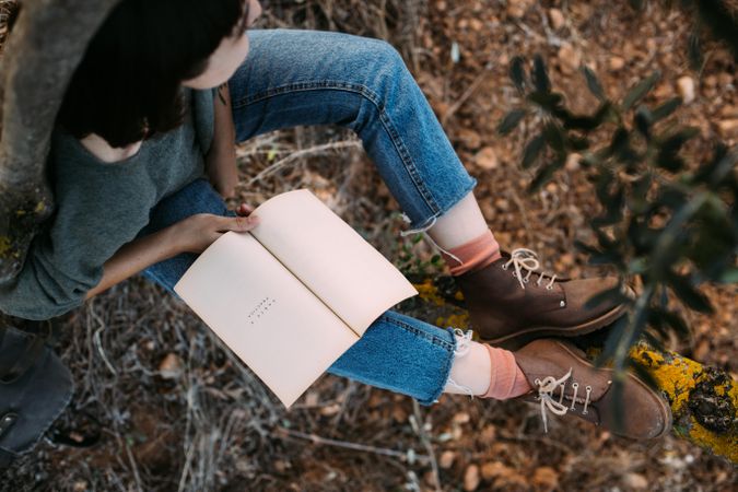 Above view of woman in jeans outdoors with book