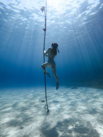 Woman underwater holding onto rope