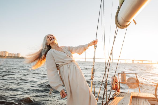 Mature woman leaning freely off a sail