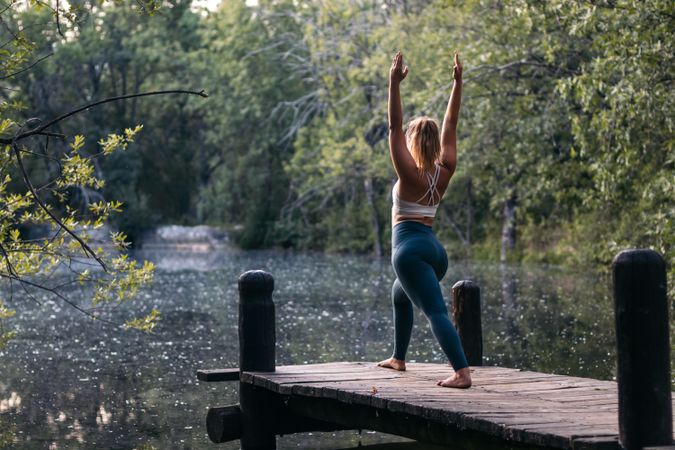 Woman in sportswear doing yoga outdoors near a lake