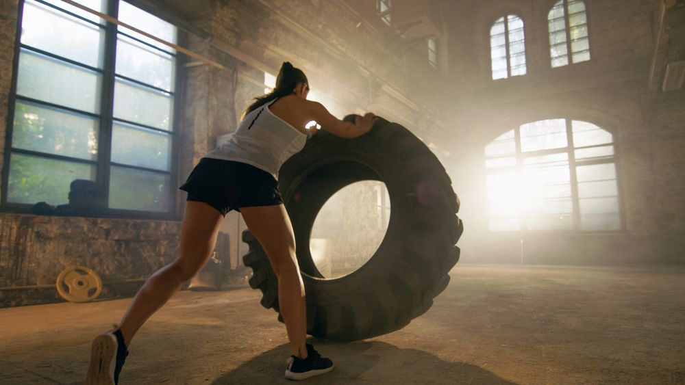 Fit Athletic Woman Lifts Tire as Part of Her Cross Fitness  Bodybuilding Training.