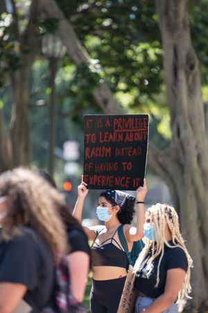 Los Angeles, CA, USA — June 16th, 2020: woman holding sign above her head at protest in park