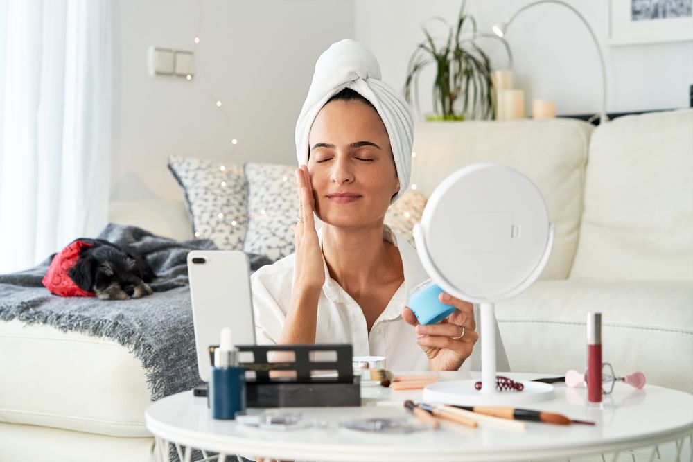 Female applying cream on face while recording video on smartphon