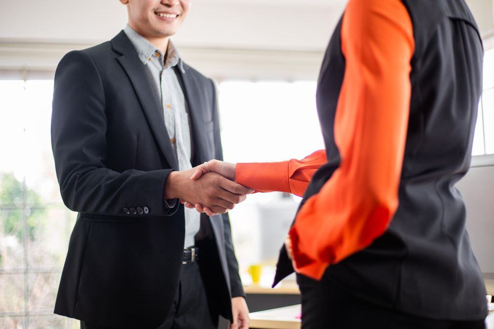 Smiling man in suit shaking woman’s hand