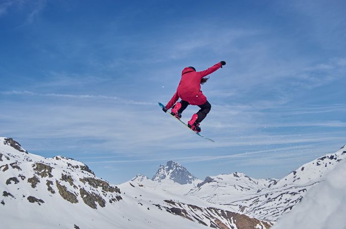 Unrecognizable snowboarder jumping on slope