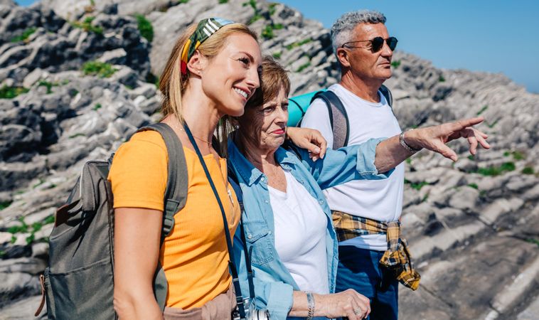 Adult daughter with her two parents looking at something in the distance on a hike
