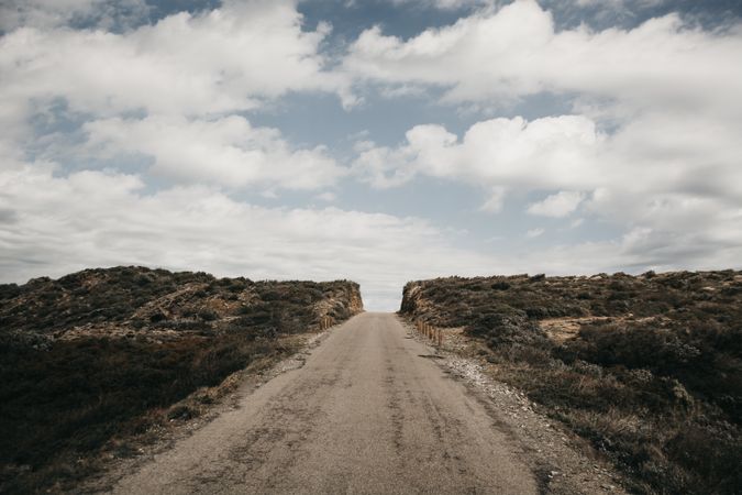 Cloudy sky over hill with road