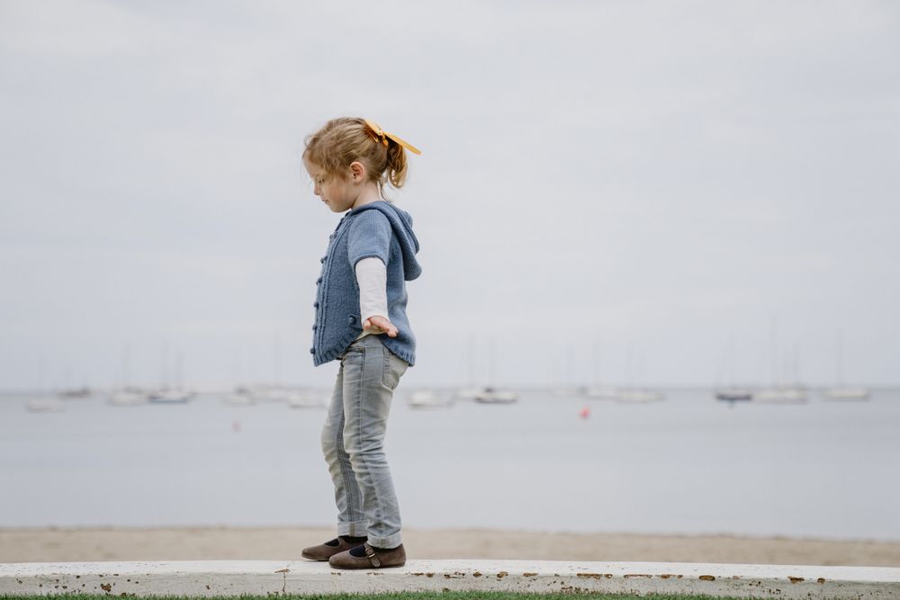 Girl balancing on border near sea