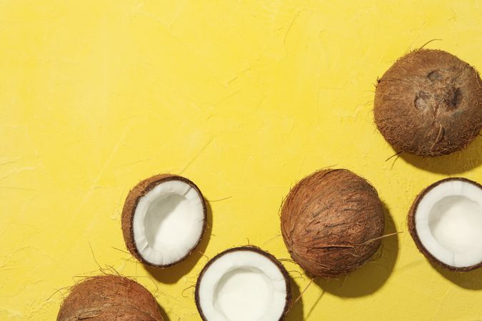 Coconut on yellow background, top view. Tropical fruit