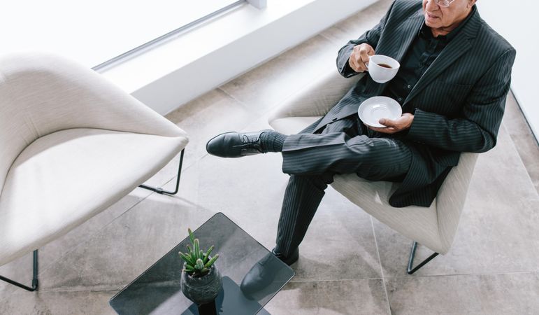 Top view of businessman sitting in office lounge having coffee
