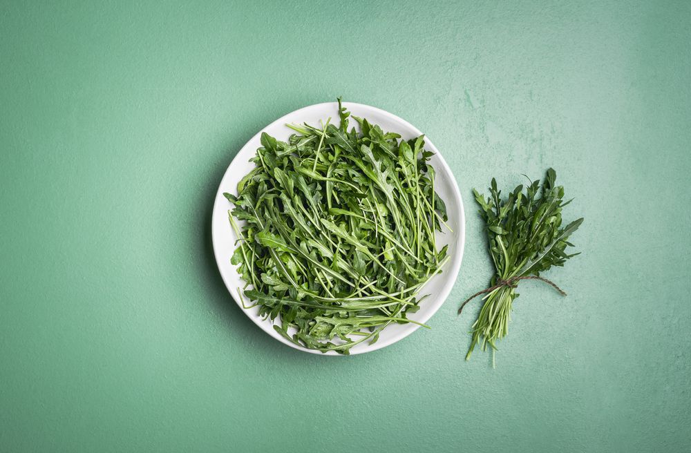 Arugula salad and arugula bundle on green table