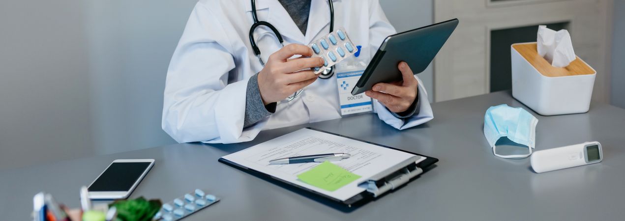 Female doctor reading drug leaflet on tablet