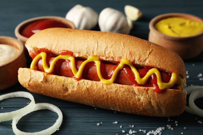 Tasty hot dog and ingredients on wooden background