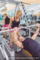 Man doing bench press with female trainer 4MX2l5