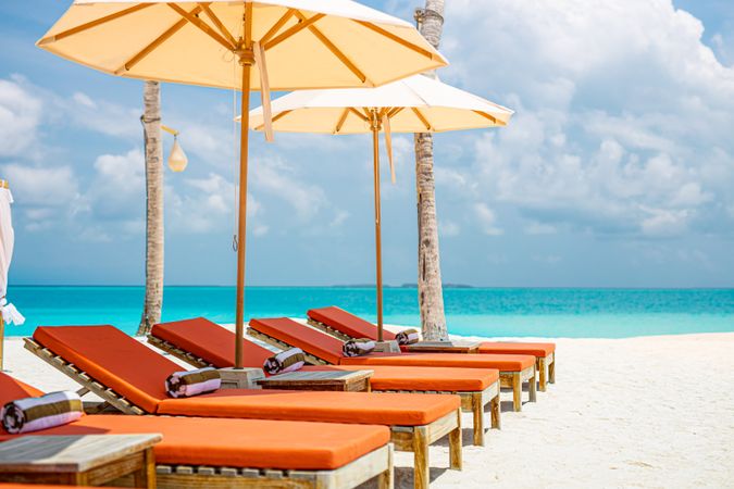 Comfortable reclining chairs with parasols on the beach, landscape