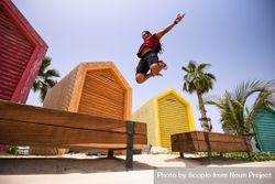 Man jumping beside colorful shacks 4AoJ80