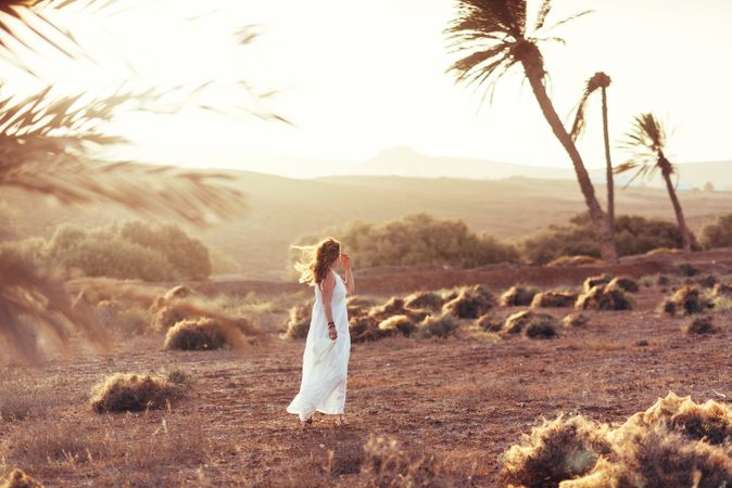 Woman in white dress in dry field in sunlight