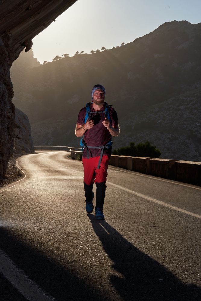 Man with backpack walking on road in mountains