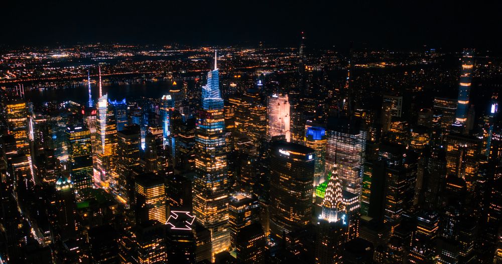 Helicopter Tour of New York City Architecture at Night. Fly-By Over Midtown Manhattan Office Buildings and Skyscrapers Towards Madison Square Garden. Aerial Urban Landscape with Lights in the Evening