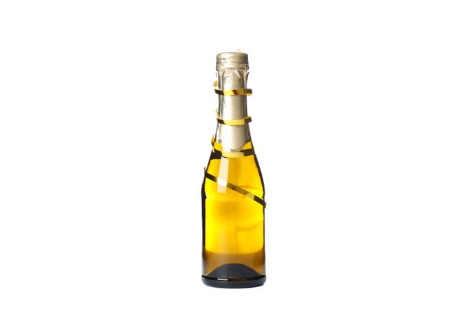 Mini champagne bottle with golden ribbon isolated on light background