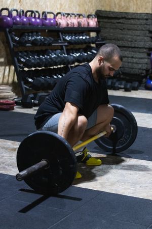 Muscular man preparing for lifting barbell