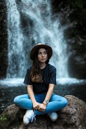 Smiling woman sitting near waterfall