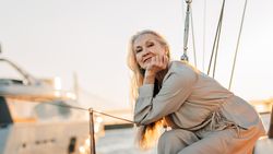 Happy older woman leaning on sailboat railings