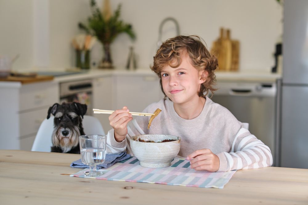 Boy eating Asian ramen and smirking