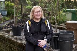 Woman sitting on brick wall in garden