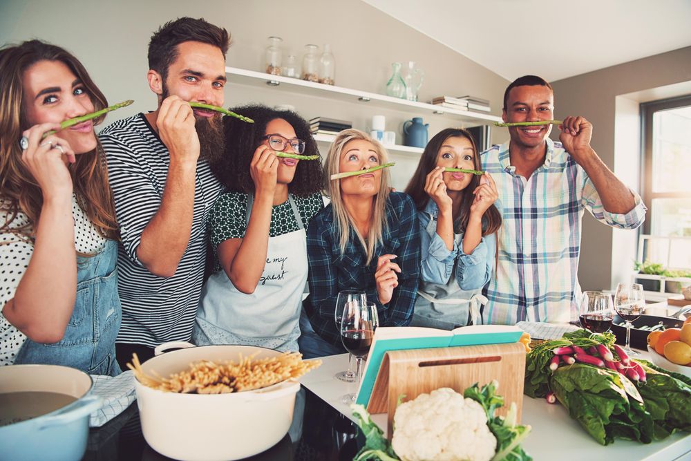Friends making silly asparagus mustache in the kitchen