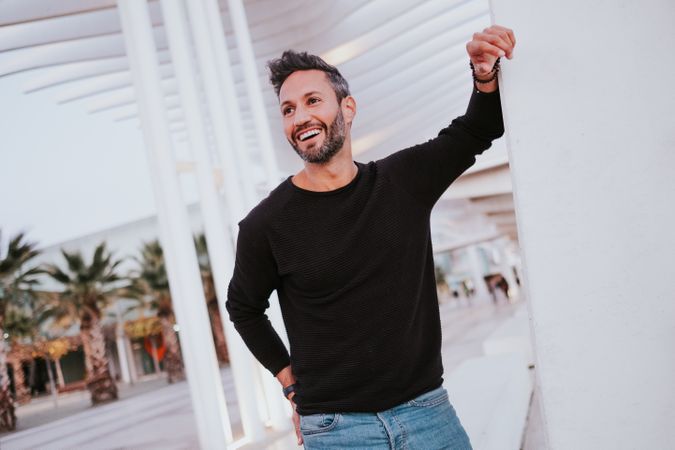 Adult stylish smiling man near grey wall on street