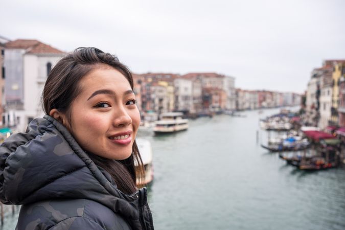 Satisfied Asian resting woman exploring old city with waterways
