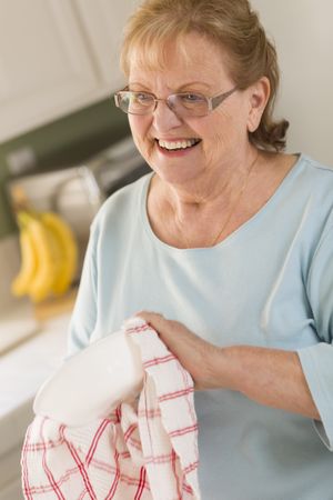 Older Adult Woman Drying Bowl At Sink in Kitchen
