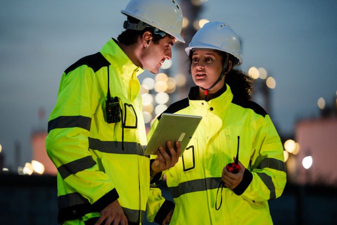 Engineer worker watching work monitor on digital tablet at refinery factory at night