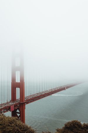 Red bridge construction over wavy dark water