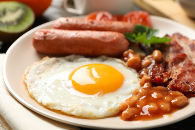 Plate of fried egg with beans, sausage and bacon