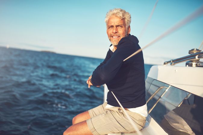 Man looking ahead while sitting on edge of sailing yacht on clear day