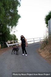 Full length shot of woman standing in street with her dog on a leash 4MGQa0